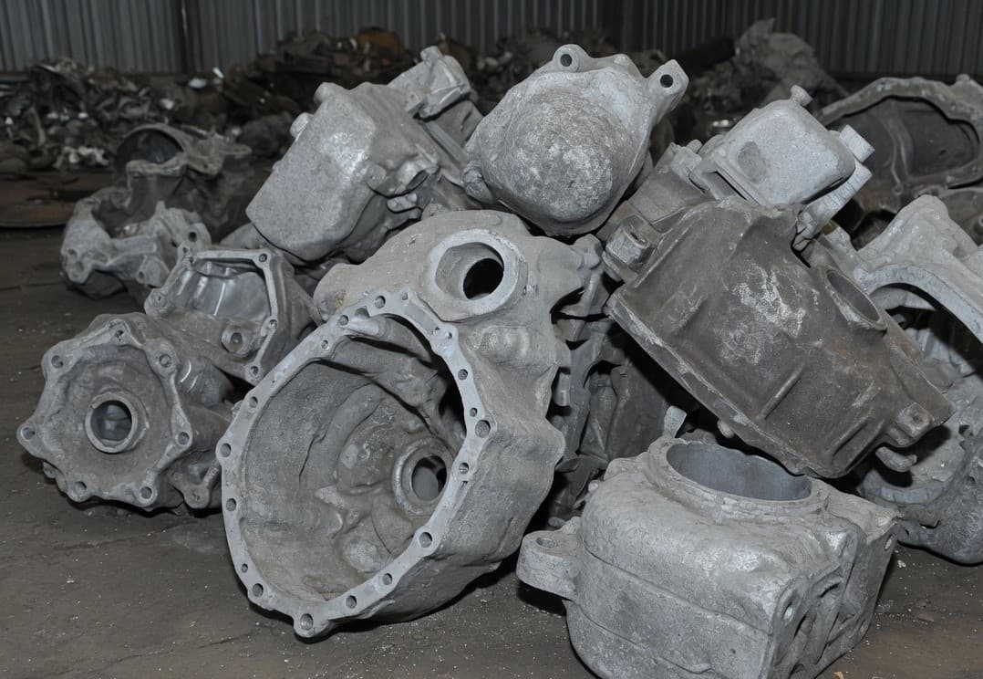 Rough grey cast aluminium housings piled on a concrete floor