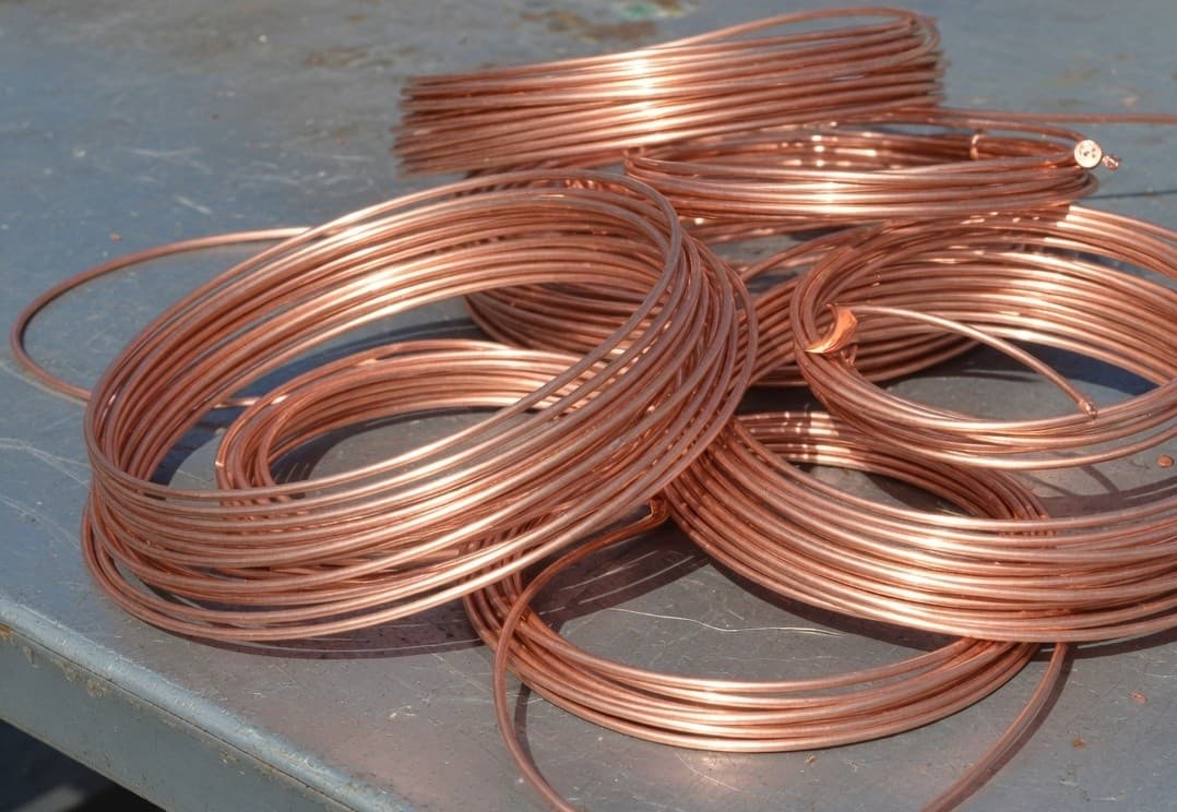 Coils of shiny salmon-pink bare copper wire on a steel table